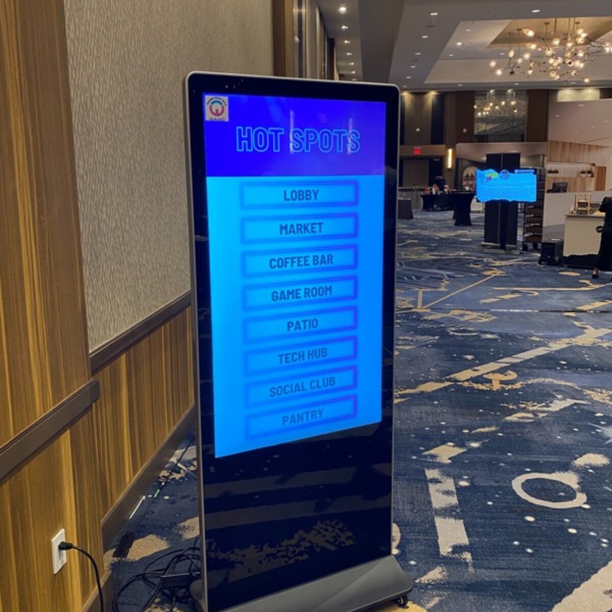 Freestanding touchscreen kiosk showing a Hot Spots wayfinding menu in a lobby